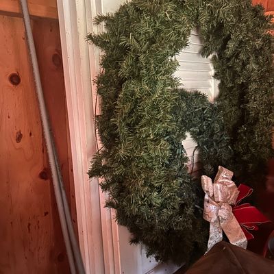 Sale Photo Thumbnail #26: Large artificial green pine Christmas wreath adorned with decorative silver and red ribbon bows.