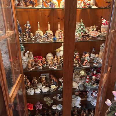 Sale Photo Thumbnail #9: A wooden curio cabinet filled with a variety of collectible porcelain figurines, bells, and decorative trinkets.