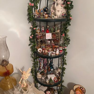 Sale Photo Thumbnail #116: Black metal dome-top corner etagere with faux greenery, filled with various collectible figurines, cherubs, porcelain trinkets, and decorative items.