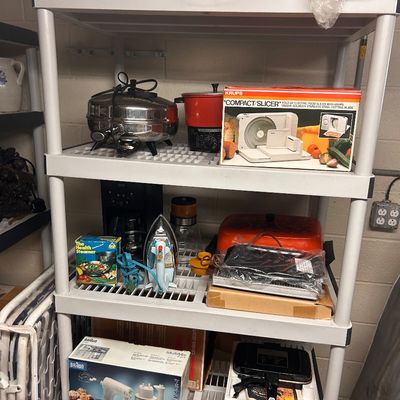 Sale Photo Thumbnail #46: Assorted vintage small kitchen appliances and housewares, including a Krups food slicer, Braun hand mixer, iron, and various countertop cookware.
