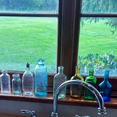 Sale Photo Thumbnail #56: Collection of vintage glass bottles in assorted colors and shapes alongside pink glass candlesticks and decorative novelties.