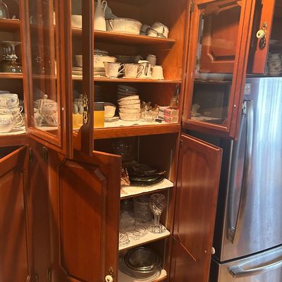 Sale Photo Thumbnail #142: Large wooden hutch cabinet with glass-front upper doors, lower storage cabinets, and shelving filled with glassware and dishware.