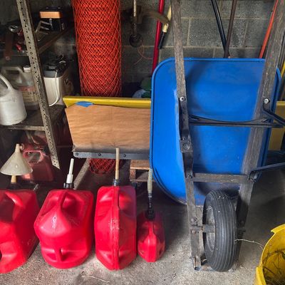 Sale Photo Thumbnail #16: Blue wheelbarrow with wooden handles alongside red plastic gas cans and various lawn and garden equipment.