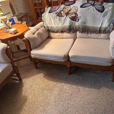 Sale Photo Thumbnail #133: Upholstered two-seater loveseat with a wooden frame, draped with a butterfly woven throw blanket, paired with a matching armchair and wooden side table.