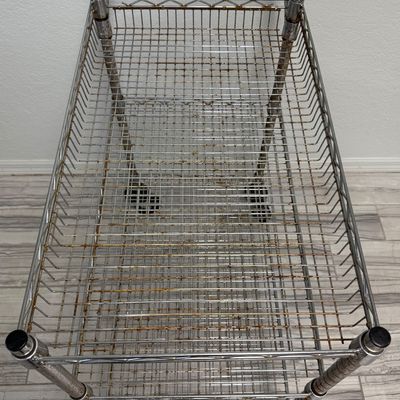 Sale Photo Thumbnail #423: This is a three-tier chrome wire utility rolling cart with a push handle and caster wheels. There is age related wear, including some surface rust. Measurement: 34”L x 18”W x 34”H (approximate). [GG]