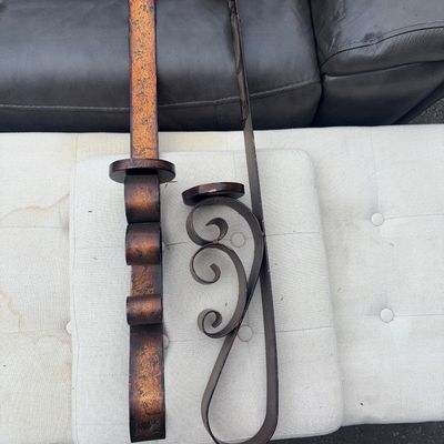 Sale Photo Thumbnail #65: Pair of wall-hanging metal decorative sconces featuring a distressed bronze and gold-tone finish. Includes one straight geometric design sconce and one scrollwork design sconce, both equipped with candle holders and hanging hooks. Show light wear and fini