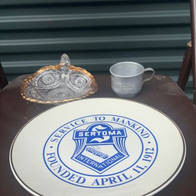 Sale Photo Thumbnail #43: An eclectic 3-piece lot of decorative tabletop and collectible items:

1. Sertoma International Commemorative Ceramic Plate, featuring the blue crest logo and "Service To Mankind - Founded April 11, 1912" with gold rim accent.
2. Cut glass/pressed glass n