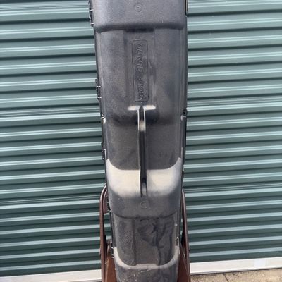 Sale Photo Thumbnail #47: Golf Guard molded black hard plastic travel case designed to protect golf clubs during transit. Features top and side carrying handles, heavy-duty latch closures, and a rugged textured exterior. Shows visible dust, scuffs, and surface wear from previous u