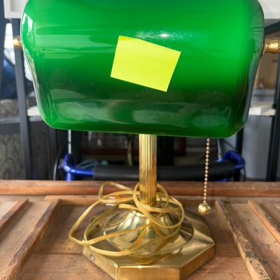 Sale Photo Thumbnail #74: Classic banker's style desk lamp featuring a polished brass-tone metal base and stem, an adjustable green cased glass shade, and a traditional pull-chain switch. Cord is wrapped around the stem. Shows light wear consistent with age and use; glass shade ap