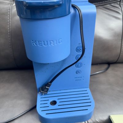 Sale Photo Thumbnail #56: Keurig K-Mini single-serve K-Cup pod coffee maker in blue. Features simple button controls for 6, 8, and 10 oz cup sizes. Plastic body construction with removable drip tray base. Shows light signs of use/wear; needs cleaning prior to use.
