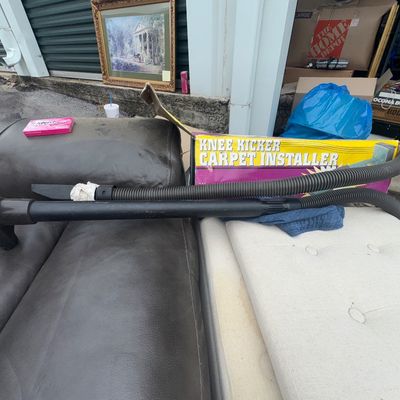 Sale Photo Thumbnail #66: Includes a Knee Kicker Carpet Installer tool in its original box along with shop vacuum hoses and attachments. Items show signs of prior use and wear consistent with typical hardware and flooring installation tools.