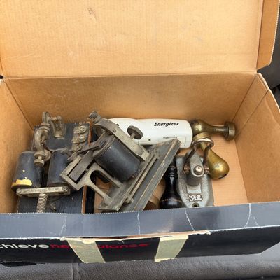 Sale Photo Thumbnail #50: Box lot containing vintage electrical items and desk accessories. Includes antique telegraph key/sounder components with coils mounted on wooden bases, cast metal stamp tools, wooden handles, and a modern Energizer battery-powered light. Items show age-ap