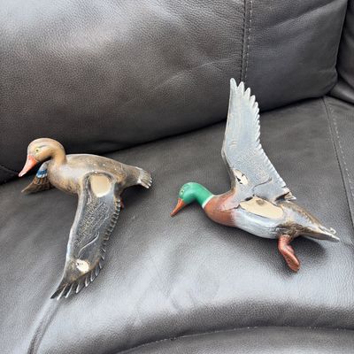 Sale Photo Thumbnail #62: Pair of detailed, hand-painted waterfowl duck figurines featuring spread wings and vibrant blue feather accents on wings. Includes one mallard drake with green head and one hen/drake in flight pose. Good pre-owned condition with light surface wear.