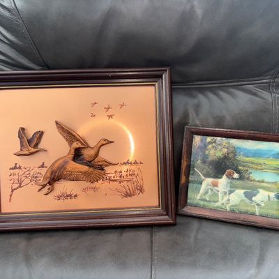 Sale Photo Thumbnail #75: A pair of framed vintage sporting-themed wall art pieces. Includes a 3D carved wood-style duck relief mounted on a copper-tone metallic sheet background inside a dark wood frame, featuring flying ducks in a marsh scene. Also includes a smaller wooden fram