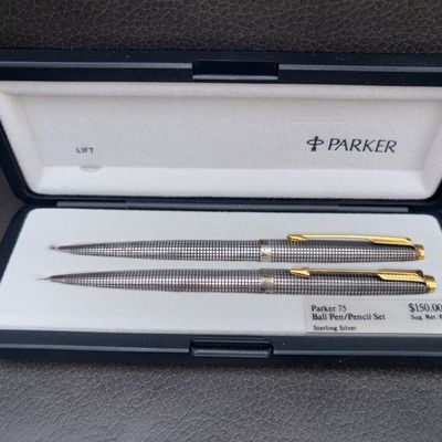 Sale Photo Thumbnail #58: A vintage Parker 75 ballpoint pen and mechanical pencil writing set featuring the classic sterling silver Cisele crosshatch pattern with gold-toned arrow clips and trim. The set comes in its original hard presentation case with interior labeling. Shows li