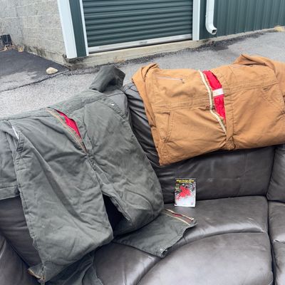 Sale Photo Thumbnail #63: Size Large. Lot includes two pairs of insulated heavy canvas work overalls/coveralls featuring red quilted linings and heavy-duty zippers. Included is one dark green/olive pair and one brown/tan pair, along with a small skier's pocket guide booklet. Items