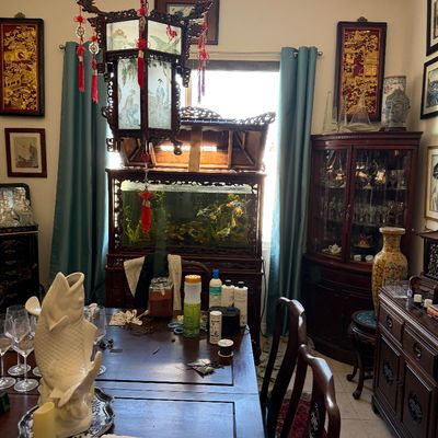 Sale Photo Thumbnail #23: Asian-inspired dining room featuring an ornate carved pagoda-style aquarium stand, a hanging glass lantern, a wooden dining set, and various oriental decor pieces.