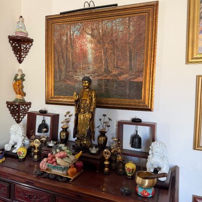 Sale Photo Thumbnail #8: Collection of Asian decor and altar items, including a gilt Buddha statue, carved stone fruit, ceramic foo dogs, and a large framed autumn forest painting.