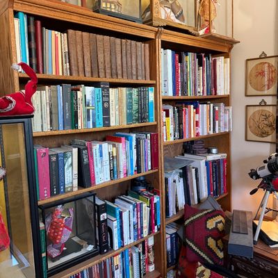 Sale Photo Thumbnail #21: Tall oak bookcases filled with books, Japanese display dolls in glass cases, kilim pillows, and a telescope.