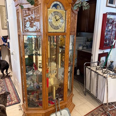 Sale Photo Thumbnail #26: Ornate wooden grandfather clock cabinet with carved panels, glass side curio shelves, and brass pendulum weights.