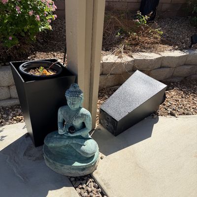 Sale Photo Thumbnail #34: Seated Buddha statue with a verdigris finish alongside modern tall black tapered planters outdoors.
