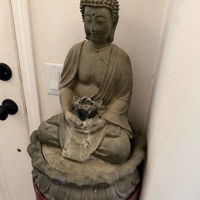 Sale Photo Thumbnail #15: Seated Buddha statue holding a lotus flower, resting on a carved lotus base atop a dark wood pedestal stand.