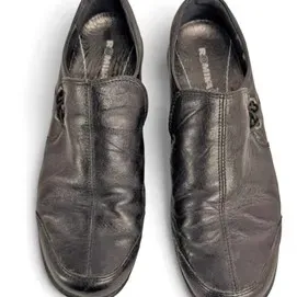 Pair of black leather Romika slip-on shoes featuring a pull tab and side accent detail, showing light wear.