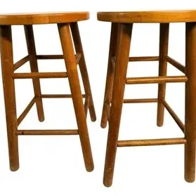 Pair of vintage backless wooden bar stools with round seats, splayed legs, and double rung stretchers.