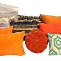 Collection of decorative accent pillows and bedding, including vibrant orange lumbar pillows, a round tufted orange velvet pillow, a teal...