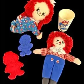 Vintage Raggedy Ann and Andy collectibles, including plush dolls, plastic cookie cutters, and a small drinking cup.
