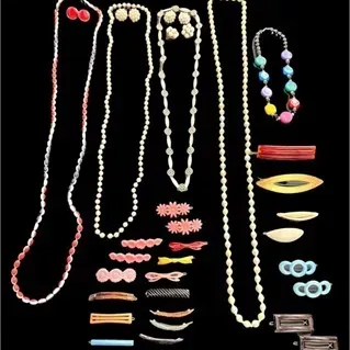 Collection of vintage costume jewelry and hair accessories, including beaded strands, clip-on earrings, and colorful barrettes.