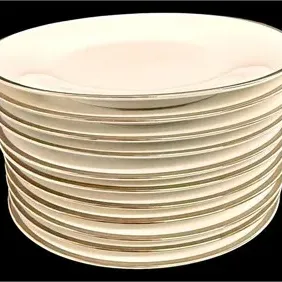 Stack of classic white porcelain plates featuring metallic gold trim along the rims.
