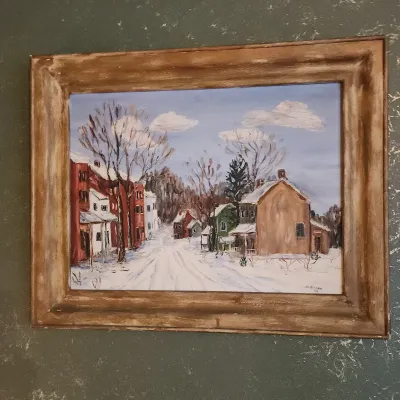 Framed oil painting depicting a snowy village street scene, signed by artist H.L. Bitzer in 1949.