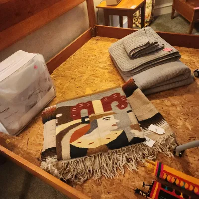 Collection of home textiles including a Westin Store mattress topper in original packaging, folded grey quilts, and a woven pictorial...