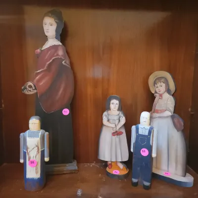 Sale Photo Thumbnail #107: Collection of folk art painted wooden cutout figures and hand-painted wooden dolls featuring 19th-century colonial and Victorian style attire.