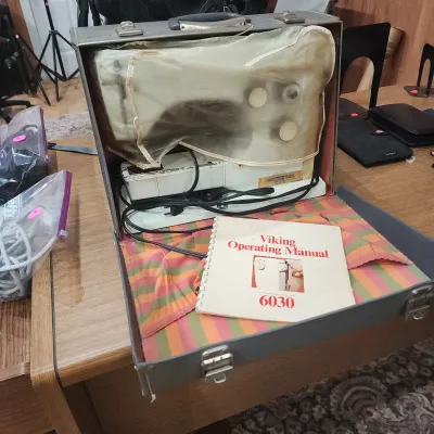 Vintage Husqvarna Viking 6030 sewing machine in a hard carrying case, complete with power cord, protective cover, and original operating...