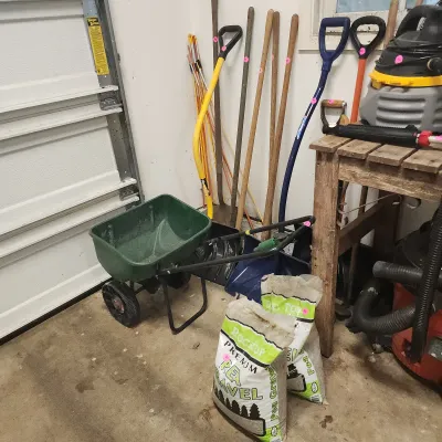 Sale Photo Thumbnail #134: Collection of lawn and garden equipment, including a walk-behind lawn spreader, snow shovels, long-handled tools, shop vacs, and bags of pea gravel.
