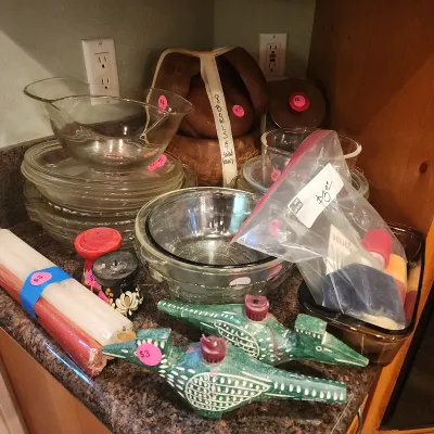 Collection of kitchenware and home decor items, including clear glass bowls and plates, a stacked wooden salad bowl set, colorful taper...