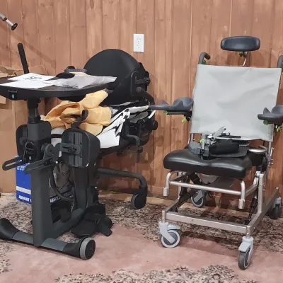 EasyStand Evolv standing frame assist device paired with a specialized mobile medical shower or commode chair, both appearing in clean,...