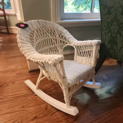 Child-sized vintage white painted wicker rocking chair with woven lattice back and wooden runners.