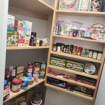 Pantry shelves filled with assorted non-perishable goods, including boxed teas, canned soups, spice jars, and decorative biscuit tins.