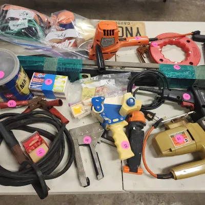Sale Photo Thumbnail #138: Assortment of vintage power and hand tools, including an orange Black & Decker drill, a yellow jigsaw, a staple gun, jumper cables, and packing tape dispenser.