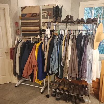 Clothing racks filled with a variety of jackets, button-down shirts, footwear, and cowboy boots, displayed alongside Southwestern textiles.