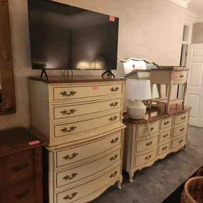 French Provincial style painted bedroom furniture, including a tall chest of drawers topped with a flat-screen TV, a matching low dresser...
