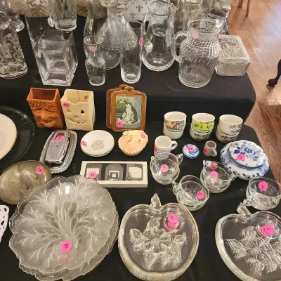 Assortment of tabletop glassware, decor, and trinkets, including clear glass pitchers, apple-shaped glass dishes, ceramic Halloween...