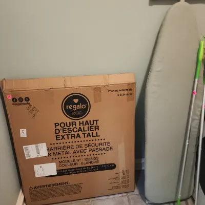 Sale Photo Thumbnail #144: Regalo Extra Tall safety gate in original box, alongside a full-size ironing board and cleaning handles.