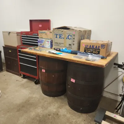 Sale Photo Thumbnail #129: Wooden workbench made from two oak barrels, alongside a red Craftsman rolling tool chest, vintage audio equipment boxes, and a wooden chest.