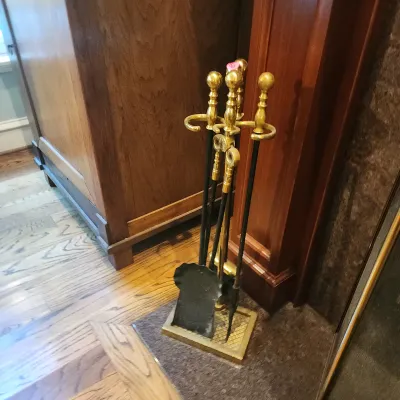 Traditional brass and black metal fireplace tool set, including a stand, shovel, poker, and tongs with decorative ball finials.