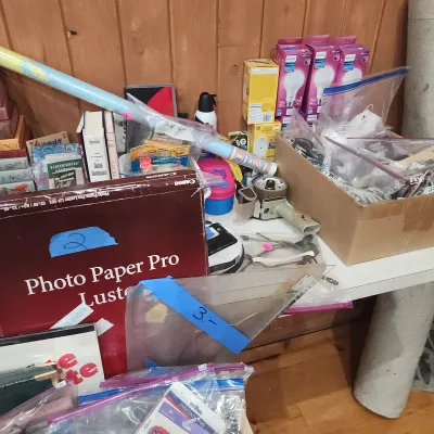 Sale Photo Thumbnail #156: Assortment of office, crafting, and household supplies including a box of Canon Photo Paper Pro Luster, Philips lightbulbs, and bagged items.
