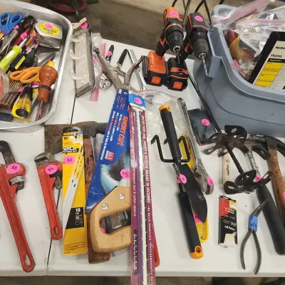 Sale Photo Thumbnail #121: Assortment of hand tools and hardware, including pipe wrenches, cordless drills, a hand saw, and hammers.